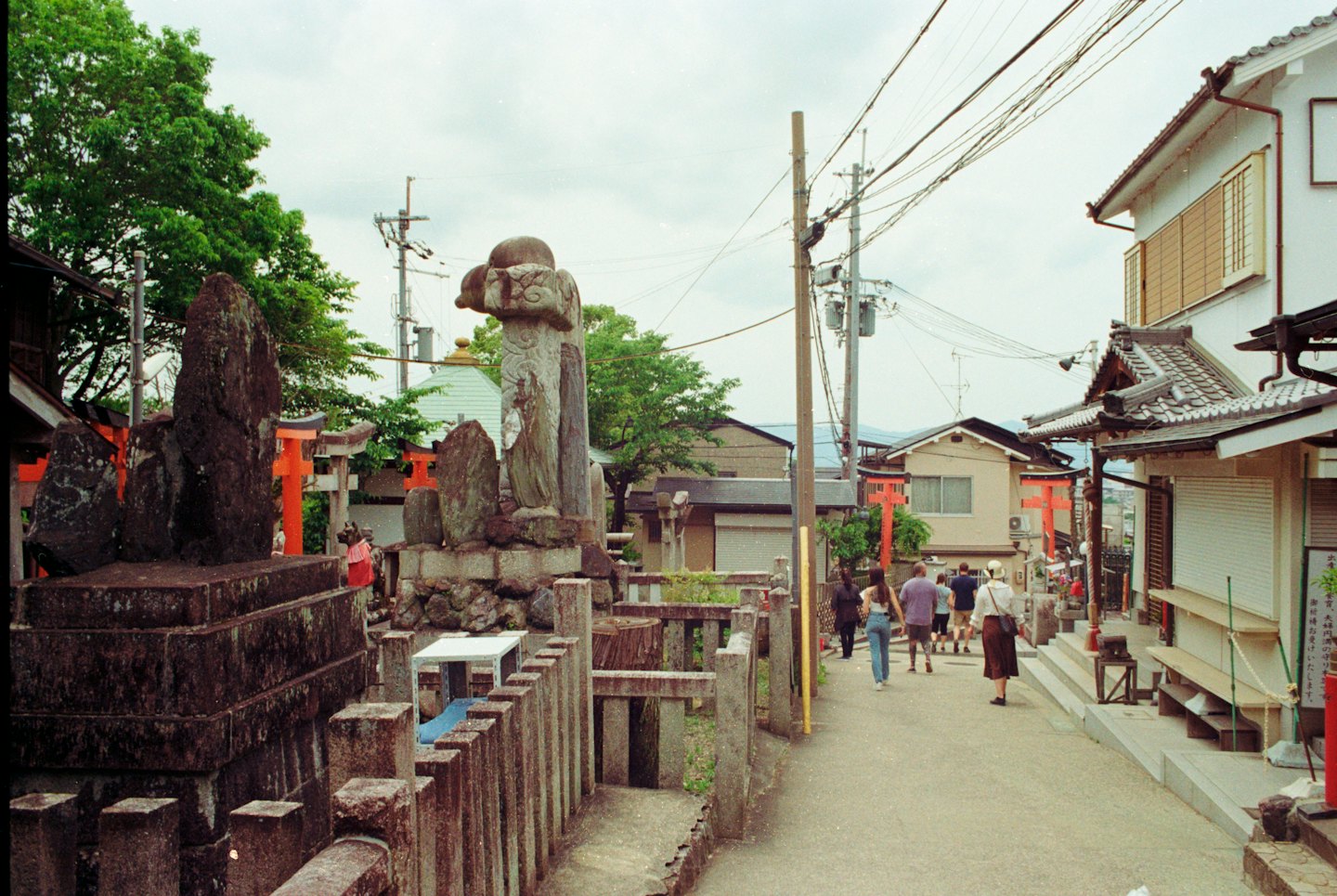 Toeristen lopen door een traditionele Japanse straat met stenen monumenten.