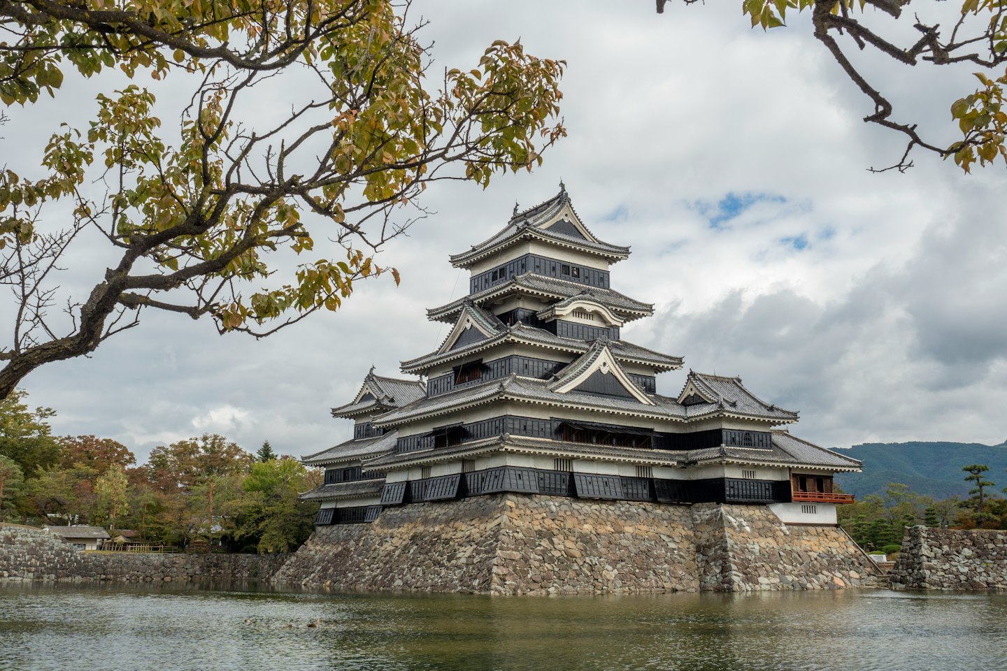 Japanse kasteel met donkere daken en zwarte muren omringd door een gracht.