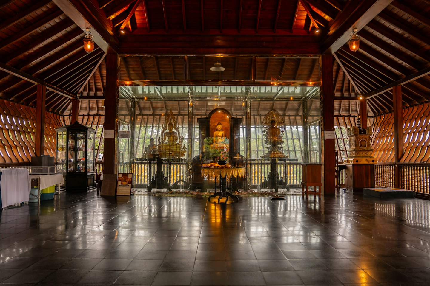 Gouden Boeddhabeelden staan in een traditionele houten tempel.